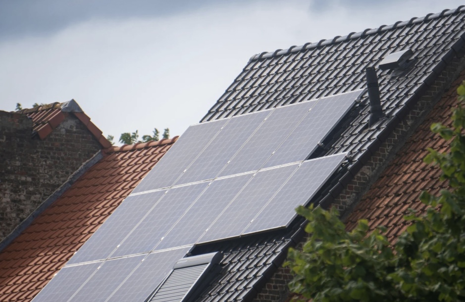 A close-up view of solar panels installed on a sloped roof, showcasing renewable energy solutions amidst a partly cloudy sky.